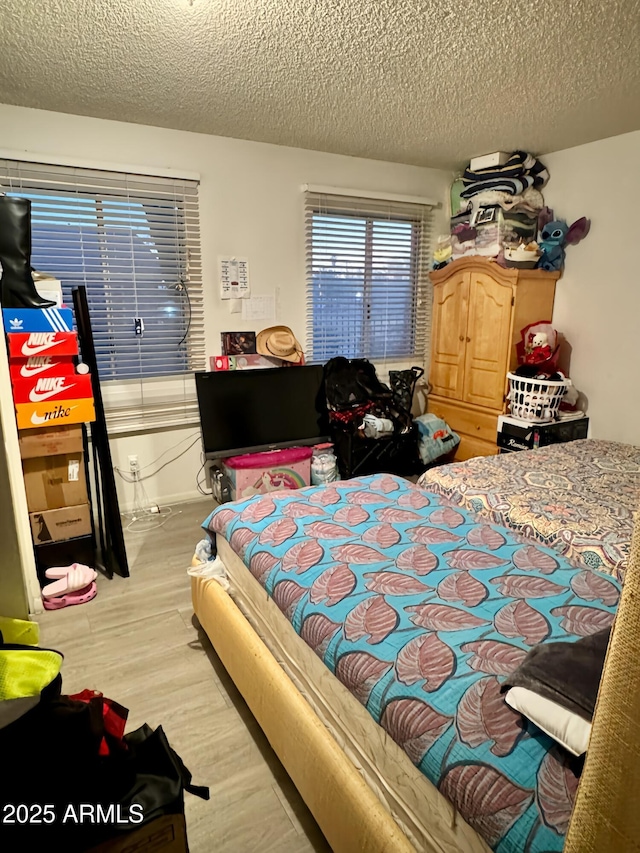 bedroom with light hardwood / wood-style floors and a textured ceiling