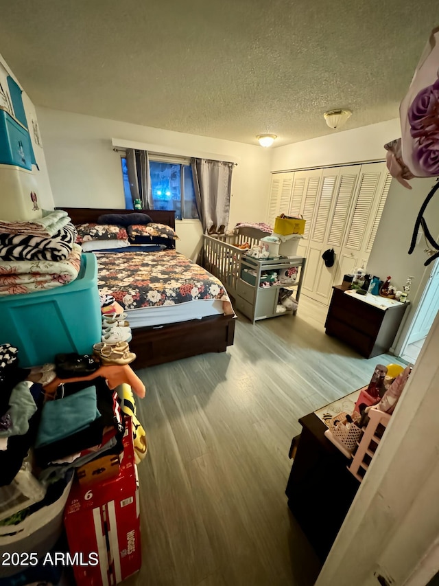 bedroom with light wood-type flooring, a textured ceiling, and a closet