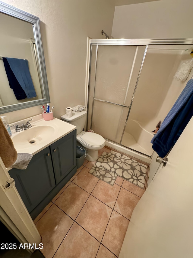 bathroom with tile patterned flooring, vanity, toilet, and an enclosed shower