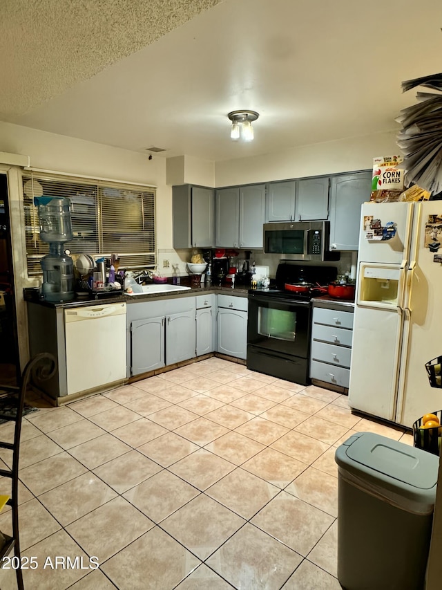 kitchen featuring gray cabinets, white appliances, sink, and light tile patterned floors