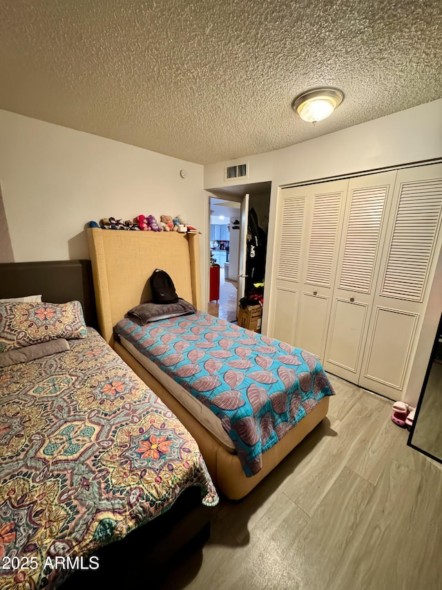 bedroom featuring a textured ceiling, light hardwood / wood-style floors, and a closet