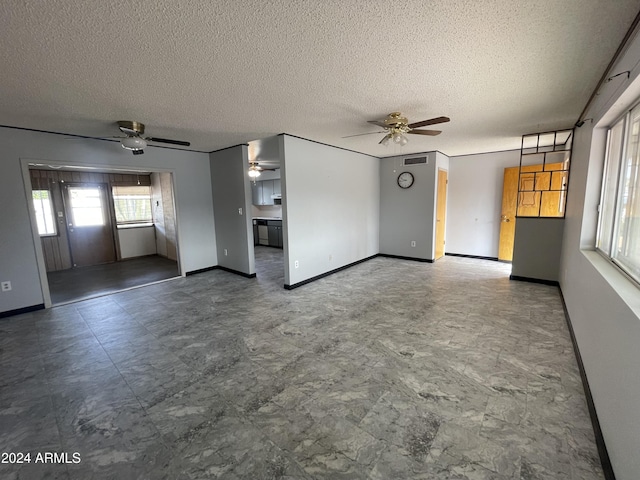 unfurnished living room with ceiling fan and a textured ceiling