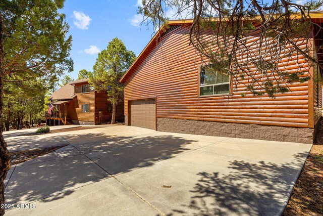 2288 Richenbacher Cir, Overgaard, AZ 85933 - view of side of home featuring log veneer siding, concrete driveway, and an attached garage