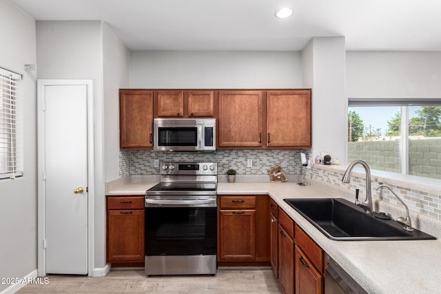 1102 N 5th St, Buckeye, AZ 85326 - kitchen with appliances with stainless steel finishes, light wood-type flooring, tasteful backsplash, light countertops, and brown cabinets