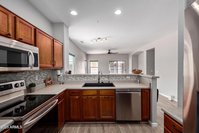 1102 N 5th St, Buckeye, AZ 85326 - kitchen with appliances with stainless steel finishes, light wood finished floors, backsplash, ceiling fan, and a peninsula