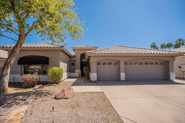 mediterranean / spanish home with a tiled roof, a garage, stucco siding, and driveway