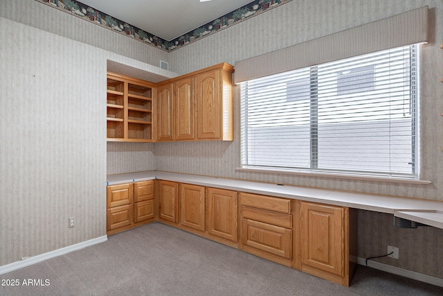 kitchen with built in study area, plenty of natural light, and wallpapered walls