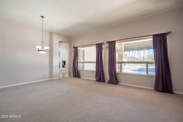 carpeted empty room featuring arched walkways and baseboards