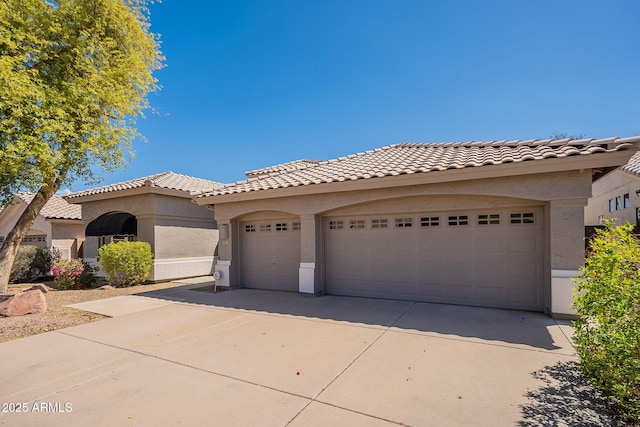 mediterranean / spanish-style home with an attached garage, driveway, stucco siding, and a tile roof