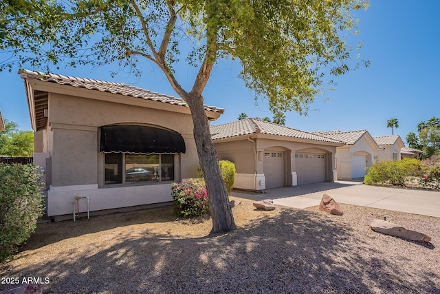 mediterranean / spanish-style house with driveway, stucco siding, a tiled roof, and an attached garage