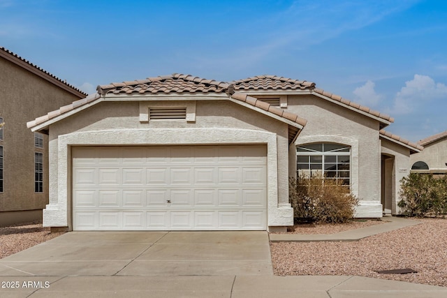 view of front of home with a tile roof, a garage, driveway, and stucco siding