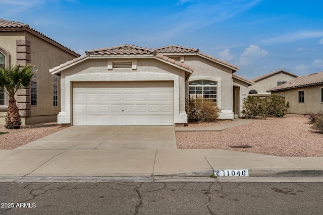 mediterranean / spanish house featuring a tile roof, concrete driveway, a garage, and stucco siding