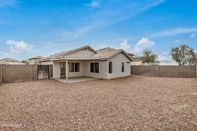 rear view of property with a patio, a tiled roof, a fenced backyard, and stucco siding