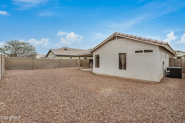 rear view of property with cooling unit, a tile roof, a fenced backyard, and stucco siding