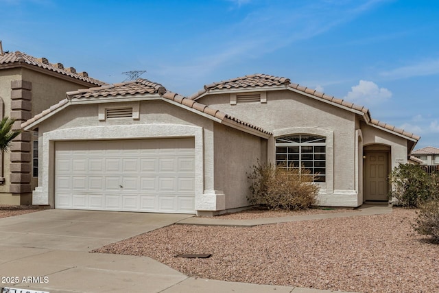 view of front of home featuring stucco siding, an attached garage, a tile roof, and driveway