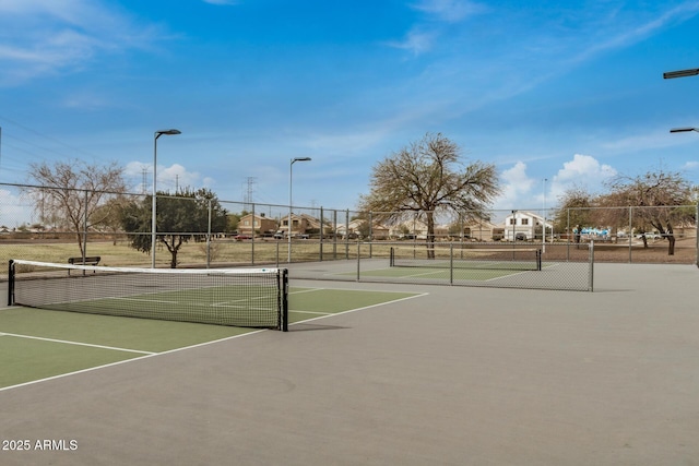 view of tennis court featuring community basketball court and fence