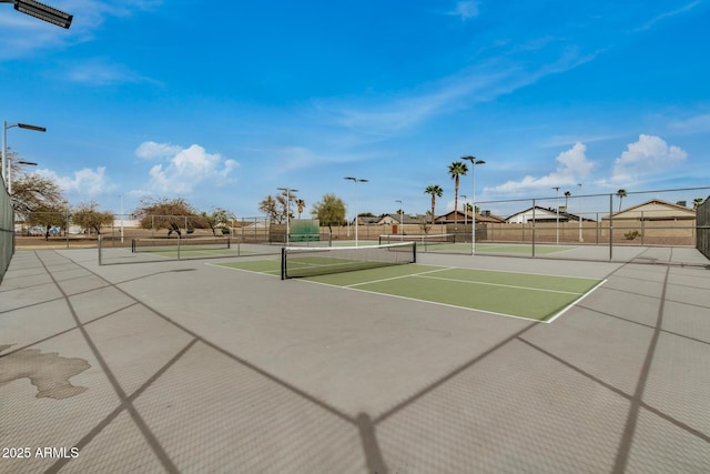 view of tennis court featuring community basketball court and fence