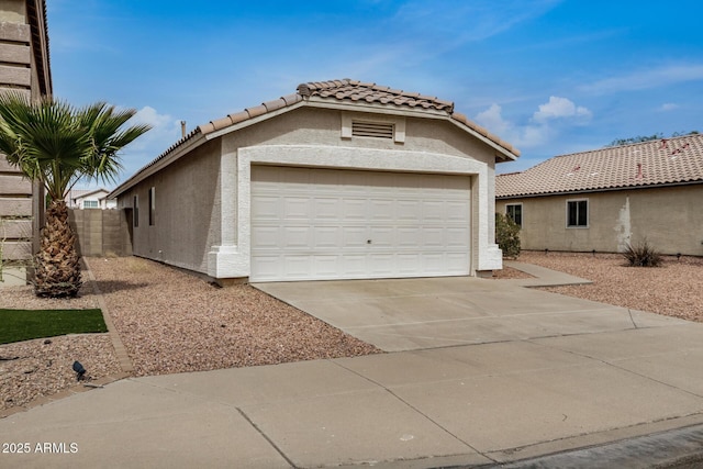 view of front of house with concrete driveway, a tiled roof, fence, and stucco siding