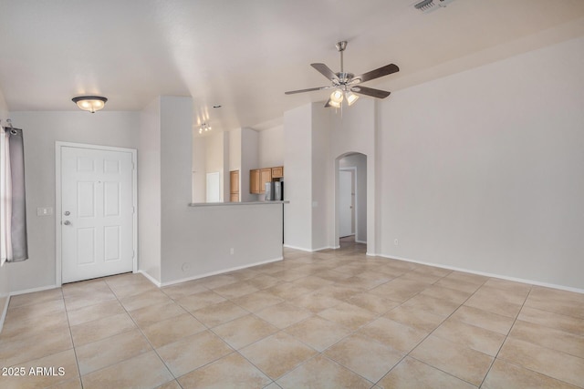 interior space with lofted ceiling, a ceiling fan, arched walkways, light tile patterned flooring, and baseboards