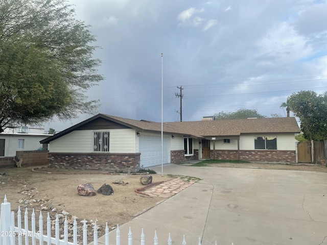 single story home with a garage, concrete driveway, brick siding, a fenced front yard, and a shingled roof