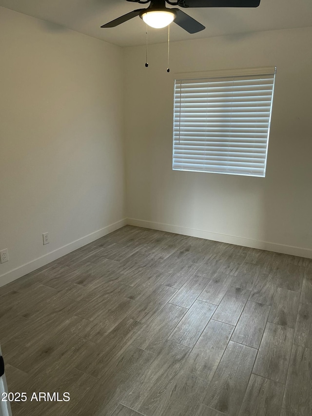 spare room featuring baseboards, wood finished floors, and a ceiling fan