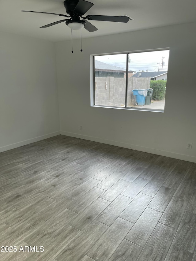 empty room featuring baseboards, ceiling fan, and wood finished floors