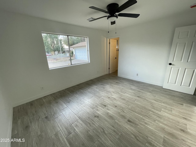 unfurnished bedroom featuring a ceiling fan, visible vents, baseboards, and wood finished floors