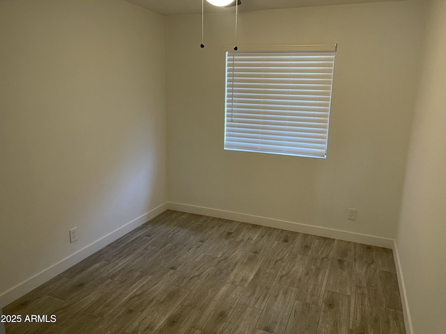 spare room featuring baseboards and wood finished floors