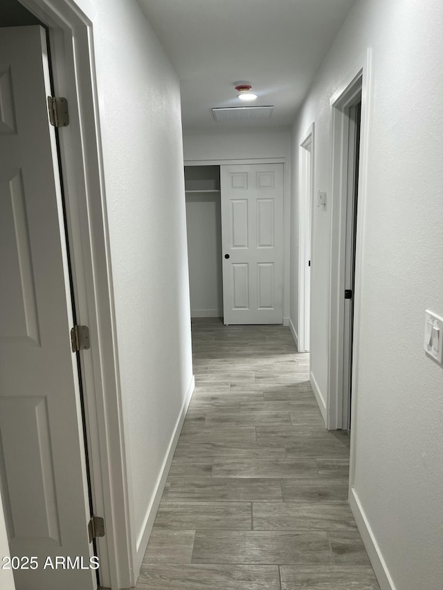 hallway featuring baseboards and wood finished floors