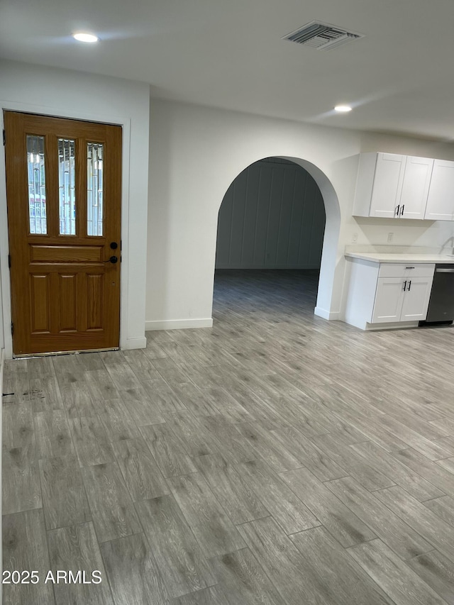unfurnished living room with recessed lighting, baseboards, arched walkways, visible vents, and light wood-style flooring