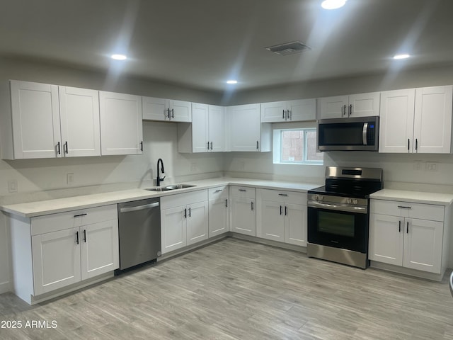 kitchen with light countertops, visible vents, light wood-style flooring, stainless steel appliances, and a sink