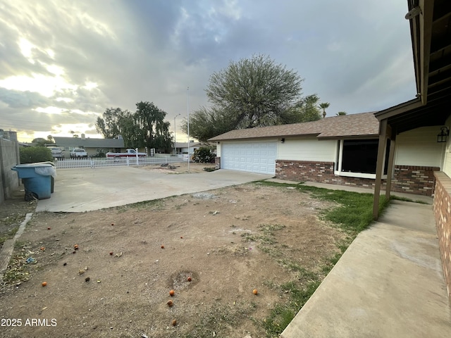 view of yard with driveway, fence, and an attached garage
