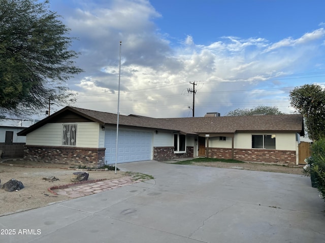 single story home featuring driveway, a shingled roof, an attached garage, and brick siding