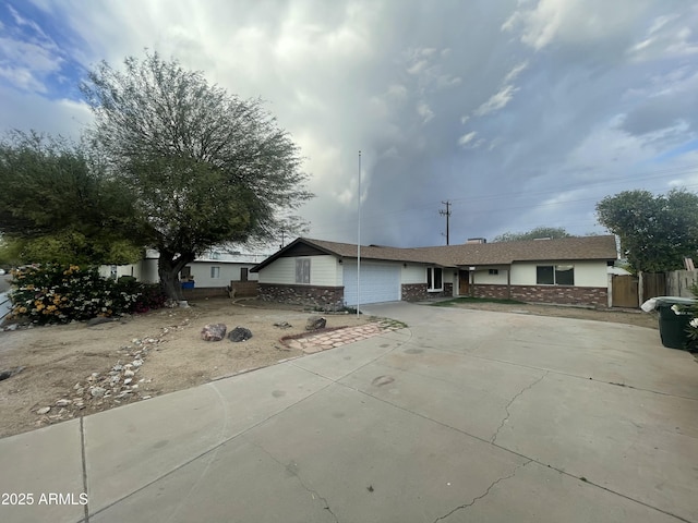 single story home featuring brick siding, concrete driveway, fence, and an attached garage