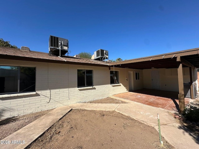 rear view of property with brick siding, central air condition unit, and a patio