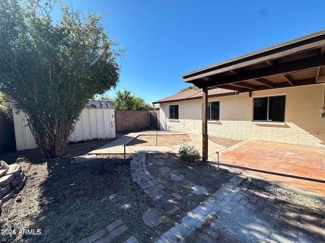 view of yard with a fenced backyard, a shed, an outdoor structure, and a patio area