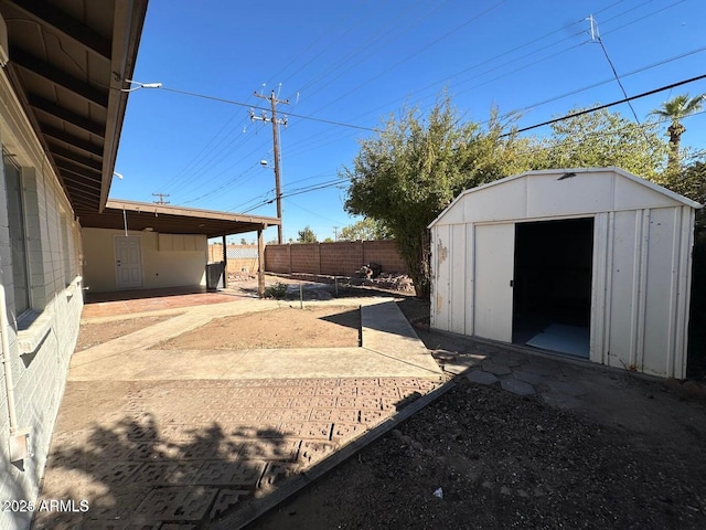 view of yard with a patio, a fenced backyard, an outdoor structure, and a shed