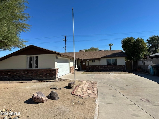 single story home featuring driveway, brick siding, fence, and an attached garage