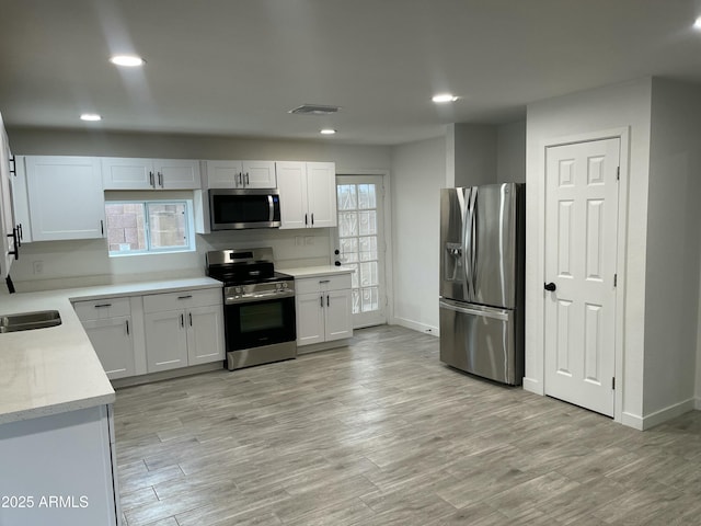 kitchen with light wood-type flooring, recessed lighting, appliances with stainless steel finishes, and a healthy amount of sunlight