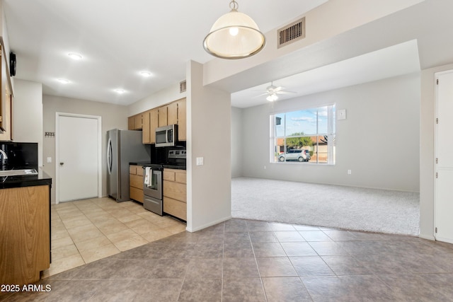 kitchen with ceiling fan, sink, stainless steel appliances, light colored carpet, and decorative light fixtures