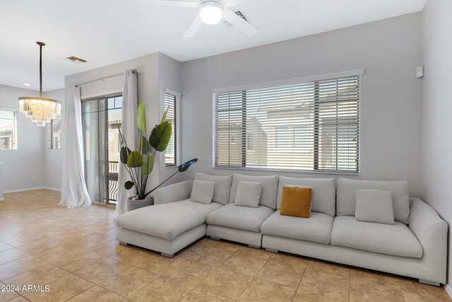 tiled living room featuring ceiling fan with notable chandelier