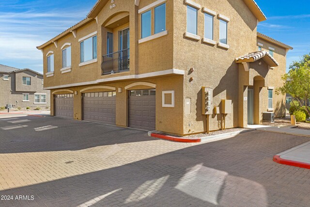 view of front of property featuring central air condition unit and a garage