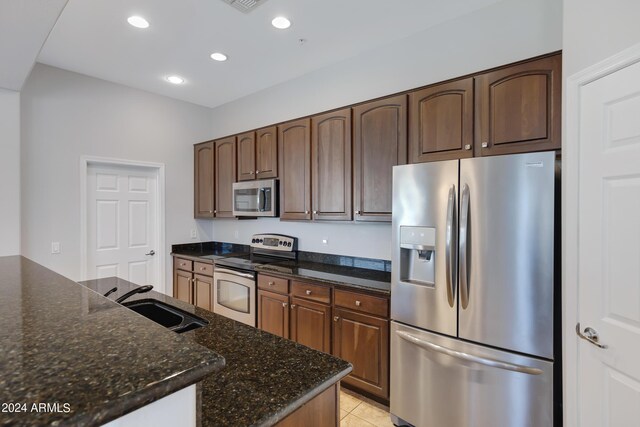 kitchen with dark stone countertops, appliances with stainless steel finishes, and sink