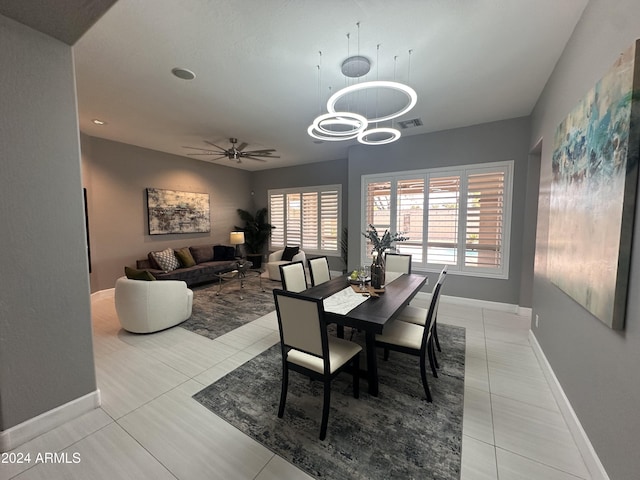 dining area featuring light tile patterned flooring and ceiling fan with notable chandelier