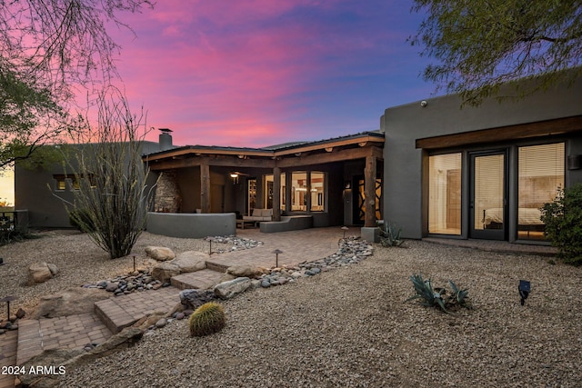 back house at dusk with a patio area