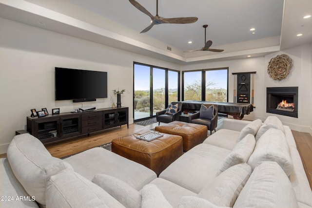 living room featuring ceiling fan, light hardwood / wood-style floors, pool table, and a tray ceiling