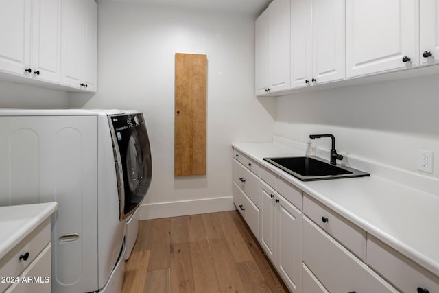 washroom with light hardwood / wood-style floors, cabinets, independent washer and dryer, and sink