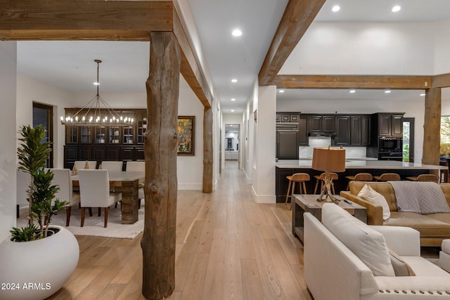 living room with beamed ceiling, a notable chandelier, light hardwood / wood-style floors, and ornate columns