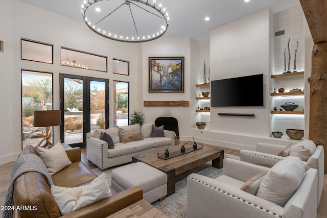 living room featuring a notable chandelier, light wood-type flooring, and a high ceiling