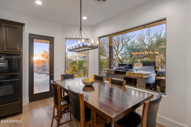 dining space featuring a wealth of natural light, light hardwood / wood-style floors, and an inviting chandelier